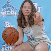 girl basketball player holding ball pointing at camera